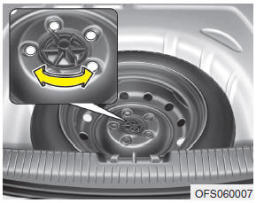 Hyundai Veloster: Removing and storing the spare tire. Turn the tire hold-down wing bolt counterclockwise.